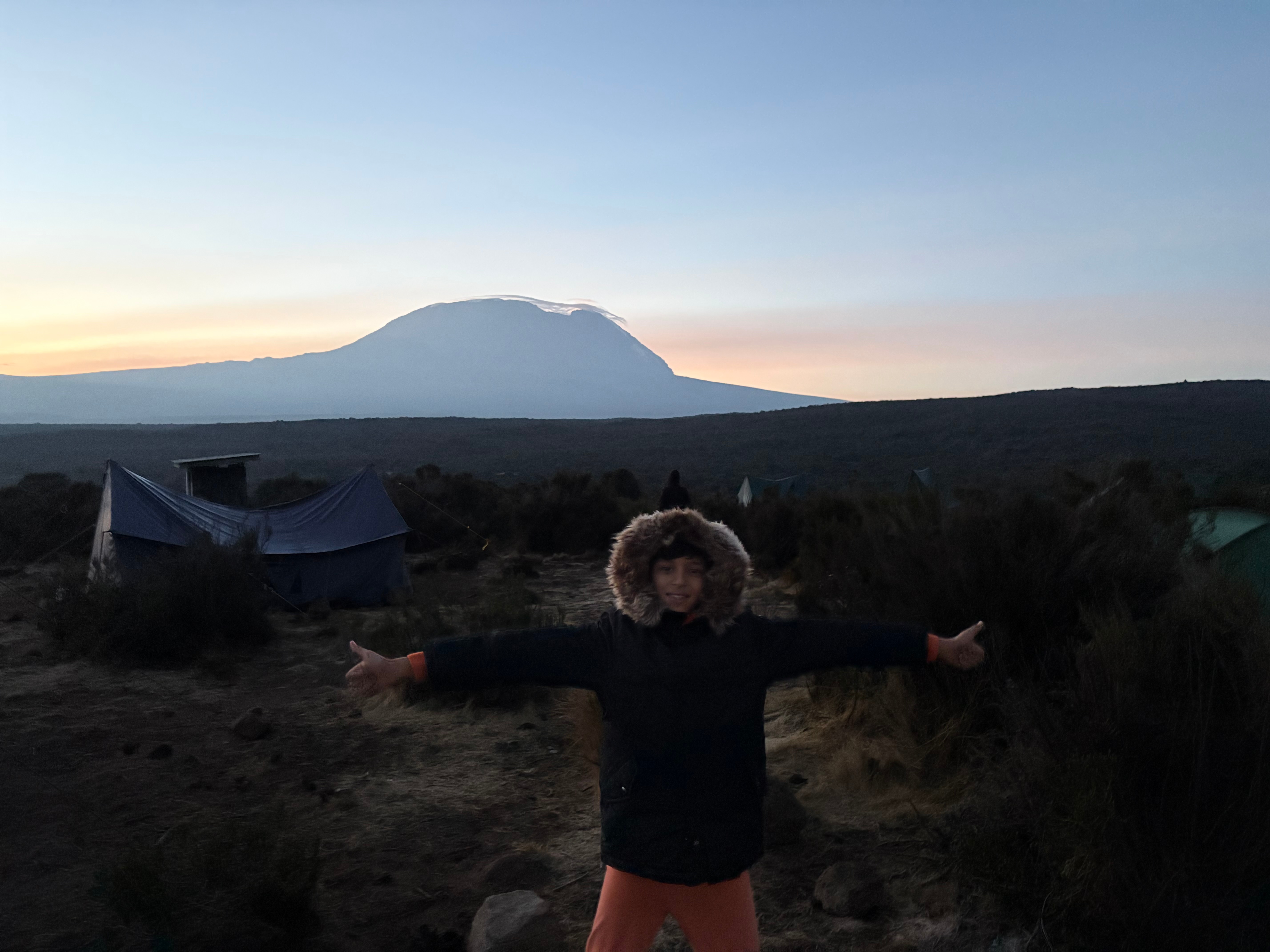 Me at base camp with Mount Kilimanjaro in the background at sunset